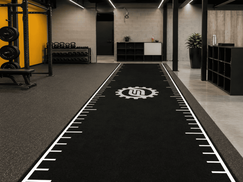 Heavy sled being pushed on custom indoor gym turf track